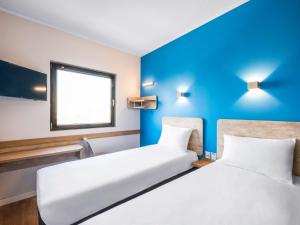 two beds in a room with blue walls at ibis budget Santiago Providencia in Santiago