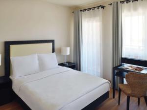 1 dormitorio con cama blanca y escritorio con ventana en Mövenpick Resort & Residences Aqaba en Áqaba