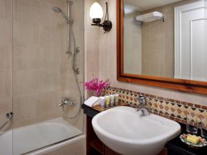 
a bathroom with a tub, sink and mirror at Mövenpick Resort & Residences Aqaba in Aqaba
