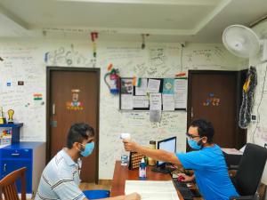 dos hombres con máscaras faciales sentados en un escritorio en Joey's Hostel Delhi en Nueva Delhi