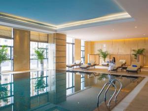 a hotel lobby with a swimming pool and chairs at Pullman Weifang in Weifang