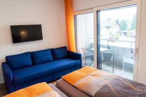 a living room with a blue couch and a balcony at Anstatthotel Schafisheim - self-check-in in Schafisheim