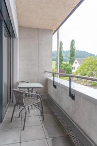 a balcony with two chairs and a table and a window at Anstatthotel Schafisheim - self-check-in in Schafisheim