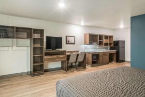 a room with a bed and a desk with a television at WoodSpring Suites Atlanta McDonough in McDonough