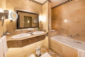 a bathroom with two sinks and a tub and a mirror at Nairobi Serena Hotel in Nairobi