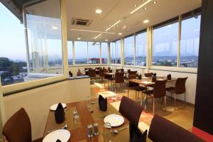 a restaurant with tables and chairs and large windows at Hotel Dayal in Udaipur