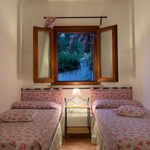 Duas camas num quarto com uma janela em Residenza Il Melograno em Budoni