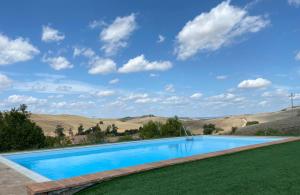 a swimming pool in the middle of a grassy field with a blue sky at Tuscany Charme Boutique House in Monteroni dʼArbia