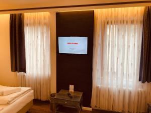 a bedroom with a tv and curtains and a bed at Hotel Kunibert der Fiese - Superior in Cologne
