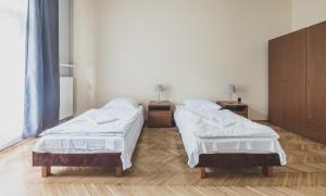 two beds in a room with a wooden floor at Cybulskiego Guest Rooms in Krakow