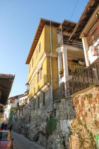 a yellow house on a stone wall next to a street at The Sunny Guest House of Veliko Turnovo in Veliko Tŭrnovo