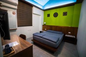a bedroom with a bed and a green wall at Ryan's Guesthouse in Xiyu