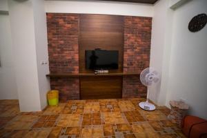 a living room with a television and a brick wall at Ryan's Guesthouse in Xiyu