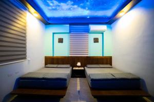 two beds in a room with a blue ceiling at Ryan's Guesthouse in Xiyu