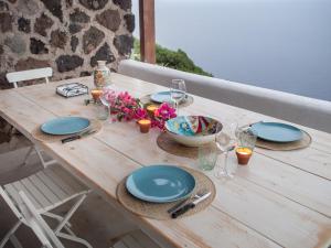 スカウリにあるDammuso sulla scogliera - Pantelleriaの木製テーブル(皿、ワイングラス付)