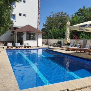 a large blue swimming pool with chairs and an umbrella at Villa Boho Cherga in Belgrade