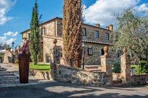 une vieille maison en pierre avec un arbre en face de celle-ci dans l'établissement Poggio Paradiso Resort & Spa, à Montefollonico