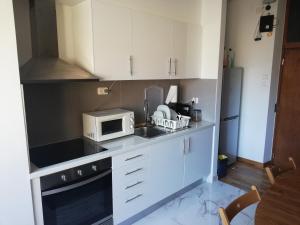 una pequeña cocina con armarios blancos y microondas en Porto Centrum Apartments, en Oporto