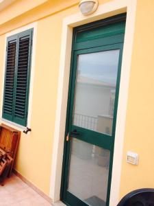 eine grüne Tür eines Hauses mit Fenster in der Unterkunft Appartamento in paese a Santa Teresa in Santa Teresa Gallura