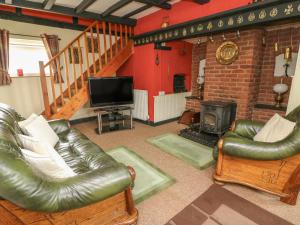 Una sala de estar con muebles de cuero y chimenea. en Caerau Farm House, en Llanidloes