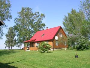 a house with a red roof on a green field at Kalda Talu in Tõlliste