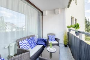 a balcony with a couch and chairs on a balcony at Relax-Apartment mit Indoor-Pool, Fitness und Netflix am Bodensee in Uhldingen-Mühlhofen
