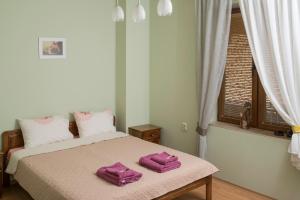 a bedroom with a bed with two purple towels on it at The Sunny Guest House of Veliko Tarnovo-Amazing View, Top Location in Veliko Tŭrnovo