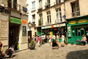 a group of people walking down a street with buildings at Le Loft du Marais in Paris