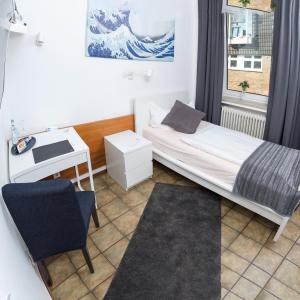 a small bedroom with a bed and a desk at Hotel Am Theaterplatz in Bremerhaven