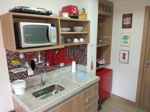 a kitchen with a sink and a tv on a shelf at Suíte Charmosa em Pedra Azul in Pedra Azul