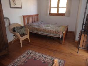 a bedroom with a bed and a chair and a window at Lantana Stone House in Lemona