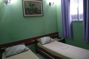 a green room with two beds and a picture on the wall at Hotel Barão De Tefé in Rio de Janeiro