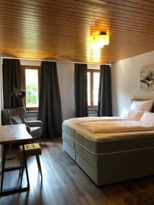a bedroom with a bed and a chair and windows at Stadtvilla mit Pool in Jestetten