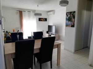 une salle à manger avec une table en bois et des chaises noires dans l'établissement REZ DE VILLA SIX-FOURS, à Six-Fours-les-Plages