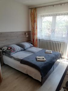 a bedroom with a bed with a blue blanket and a window at Pokoje Gościnne U Babuni in Bukowina Tatrzańska