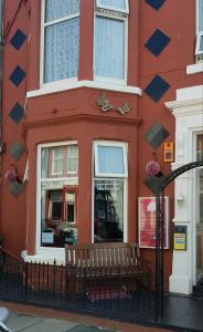 un edificio rojo con un banco delante de él en Grange House Hotel en Blackpool