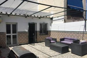 eine Terrasse mit lila Möbeln und ein Gebäude in der Unterkunft CASA REFORMADA CON TERRAZA/WIFI/AIRE ACONDICIONADO in Sevilla