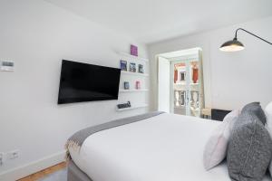 a white bedroom with a bed and a flat screen tv at WHome | Prime Location Luxury Apartment in Lisbon