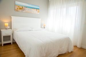 a bedroom with a white bed and a window at L1 Apartamento O Grove Centro, Aire acondicionado, parking in O Grove