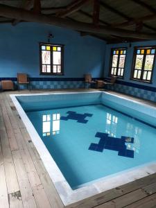 a large swimming pool with a blue wall and windows at Pousada Pegada da Onça in Tapiraí