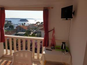 a room with a balcony with a table and a television at Apartments & Rooms Zlatica Hvar in Hvar
