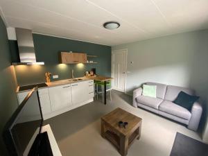 een keuken en een woonkamer met een bank en een tafel bij Appartement Duinweg in Onstwedde