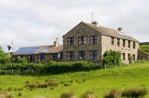 una casa antigua con paneles solares al lado de un campo en YHA Langdon Beck, en Holwick