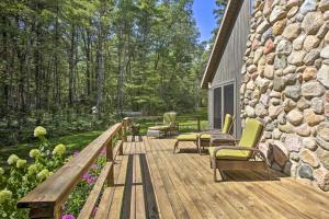 una terraza de madera con sillas y una pared de piedra. en Tranquil Riverside Home with Wraparound Deck and Views en Baldwin