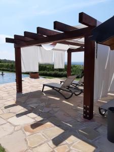 a patio with two lounge chairs under a wooden pergola at Relais Juliette in La Morra