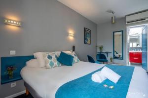 Un dormitorio con una gran cama blanca con toques azules en Un Hotel sur le Port, en La Rochelle