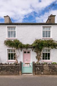 a white house with a pink door and windows at Maggie Puddle Cottage in Grange Over Sands