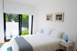 a white bedroom with a bed and a large window at Casa da Ribeira Guesthouse in Alvares