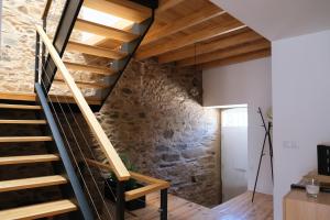 a wooden staircase in a room with a stone wall at Casa da Ribeira Guesthouse in Alvares