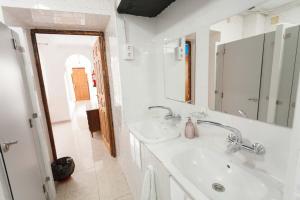 a white bathroom with a sink and a mirror at Onefam Catedral in Seville